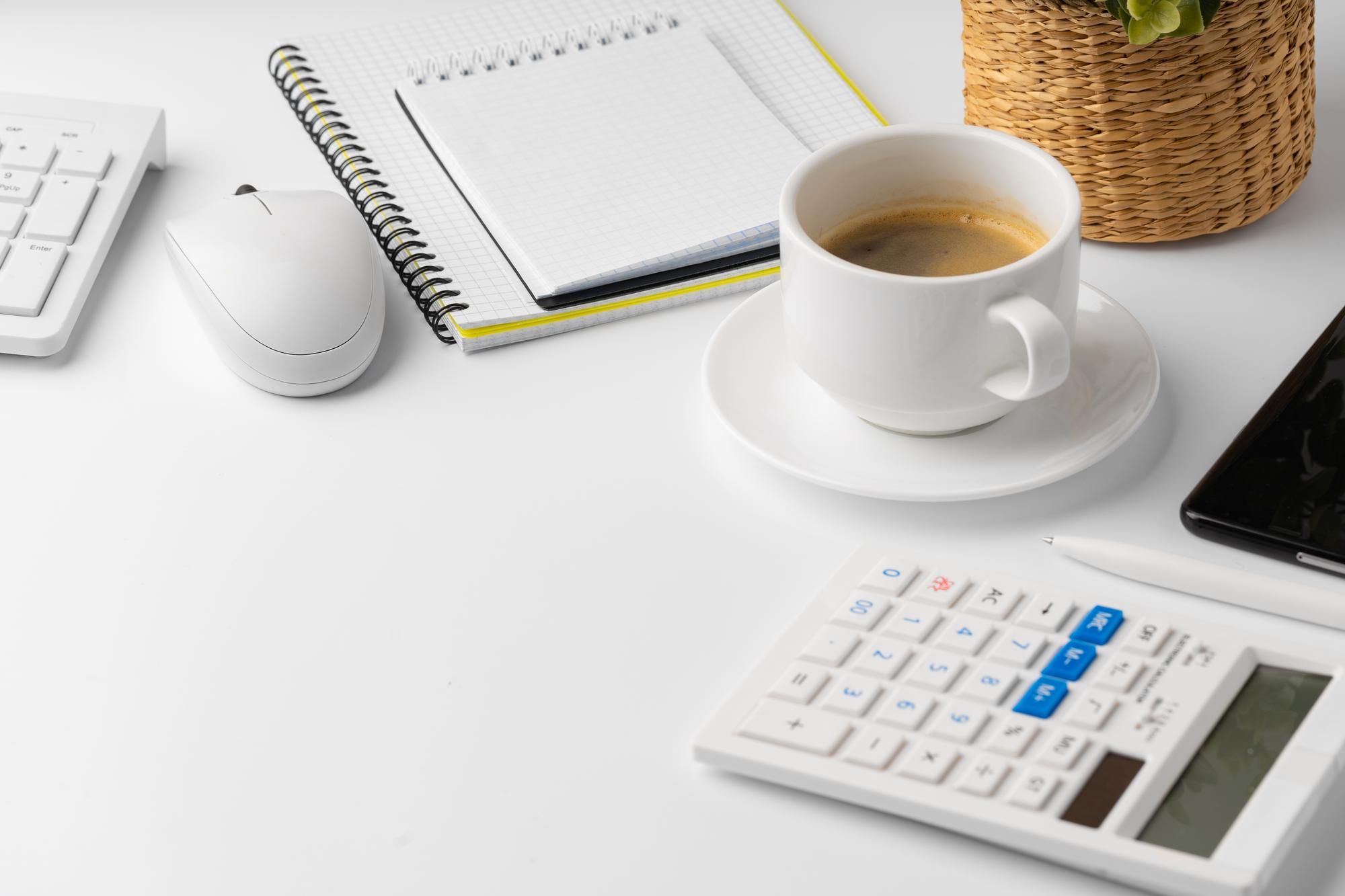 Minimaler Schreibtisch mit Taschenrechner und Kaffeetasse